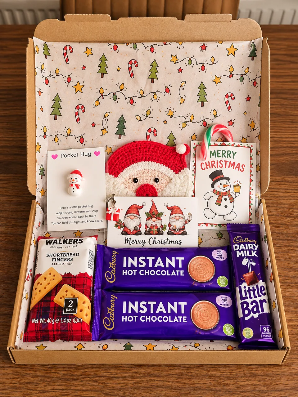 Open Christmas gift box with hot chocolate, shortbread, chocolate and festive keepsakes