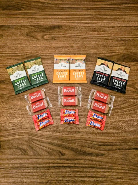 Coffee bags, chocolate and biscuits laid out on a wooden table
