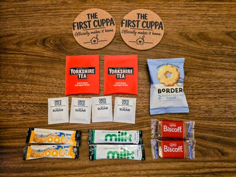The First Cuppa tea gift contents and coasters arranged on a wooden table